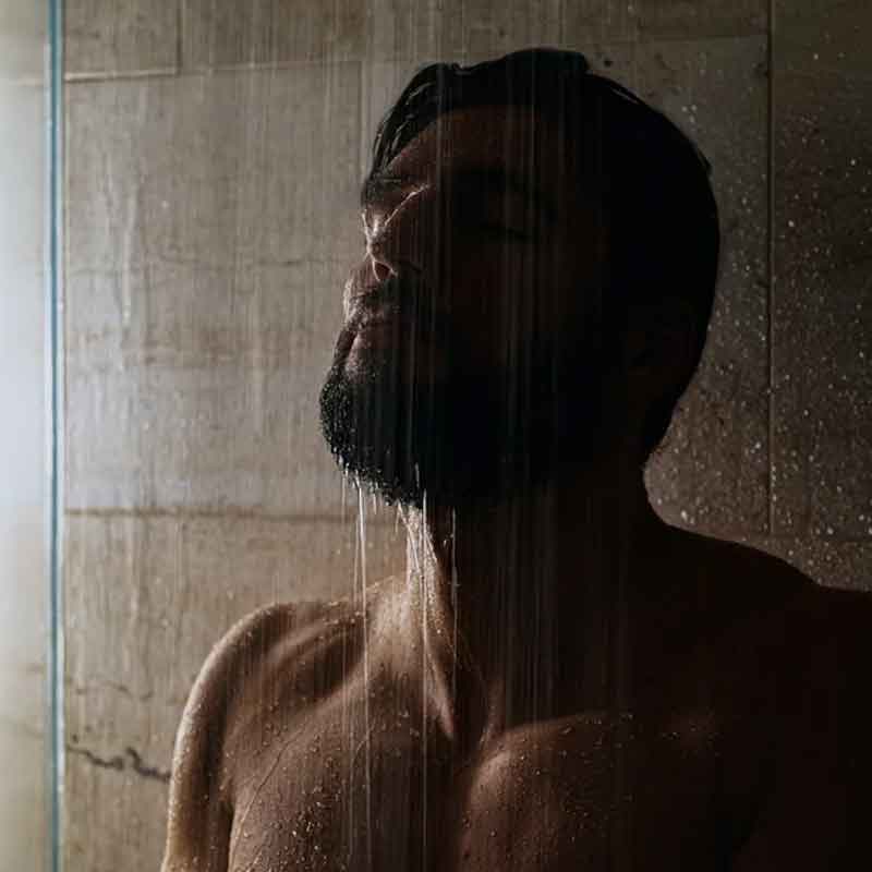 a man bathing with a chastity cage on (off camera)