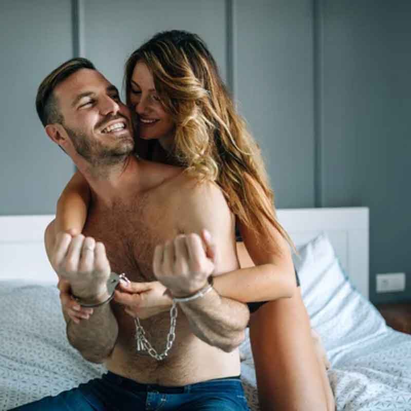 a man in physical control of a woman, both laughing in bed