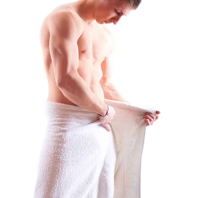 a man inspecting his genitalia under a towel during a long term chastity session
