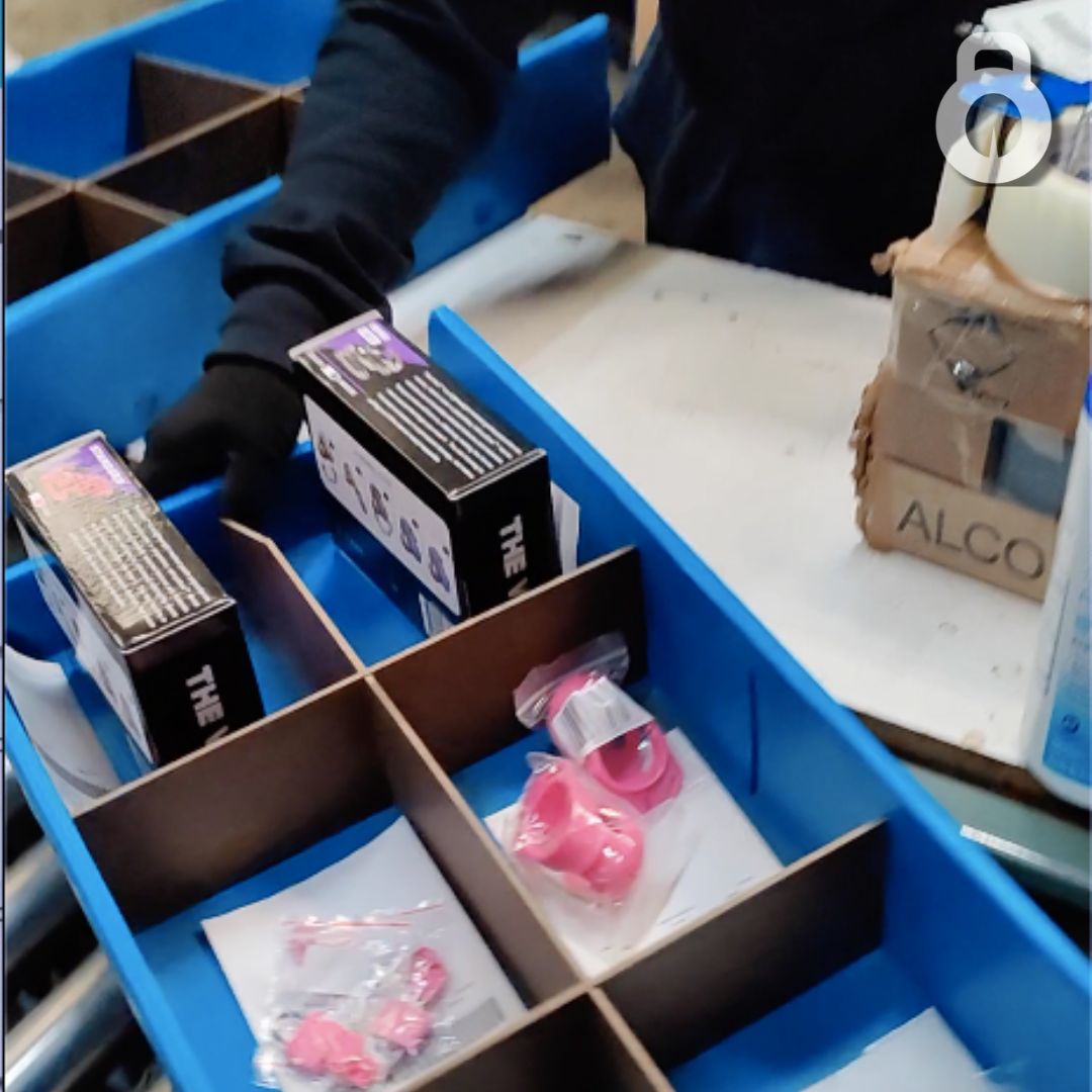 warehouse tray of The Vice chastity orders tray of multiple Vice chastity products being pushed onto conveyor belt.